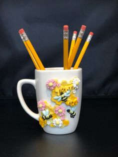 a cup with pencils in it sitting on a table next to a black background