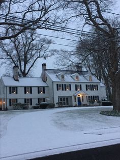 a large white house sitting on the side of a snow covered road