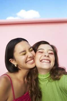 two young women are smiling and hugging each other while they both have their eyes closed