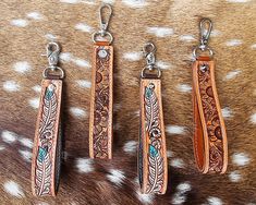 three different types of leather keychains on a cowhide surface with white spots