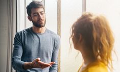 a man standing in front of a mirror talking to a woman who is holding her hand out