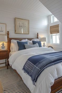 a bed with white sheets and blue pillows in a bedroom next to two lamps on either side of the bed