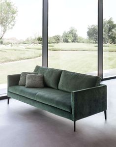 a green couch sitting in front of large windows