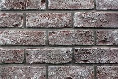 an old brick wall is shown in grey tones, with little patches of snow on the bricks