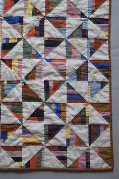 a quilted wall hanging on the side of a building with many different colored strips