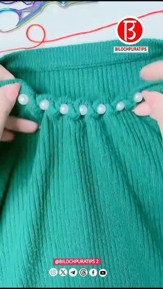 the woman is working on her green dress with pearls and beads in front of scissors