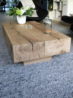 a coffee table made out of wood with flowers in the vase and candles on top