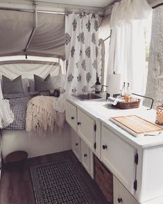 the inside of a camper with a sink, stove top and bed in it