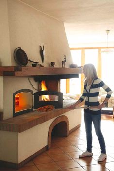 a woman standing in front of an open fire oven