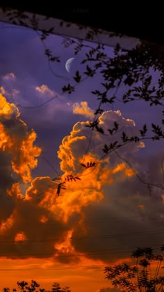 the sun is setting behind some clouds with trees in the foreground and an orange glow on the horizon