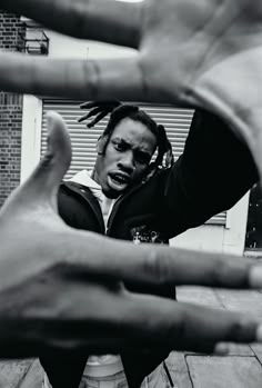 a black and white photo of a man with dreadlocks holding his hands in the air