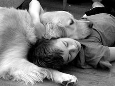 a woman laying on the floor next to a dog with it's head on her chest