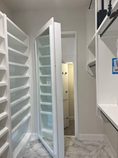 an empty walk in closet with white shelving and glass doors on the door way