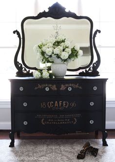 a dresser with a mirror and flowers on it