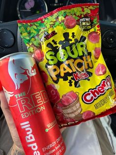 a person holding two bags of fruit flavored snacks in their hand while sitting in a car