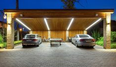 two cars parked under a covered area with picnic tables in the background at night time