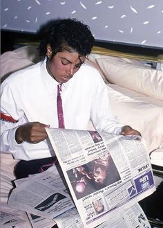 a man sitting in bed reading a newspaper