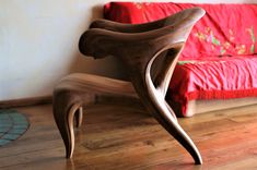 a wooden chair sitting on top of a hard wood floor next to a red couch