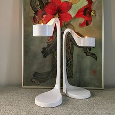 a white table lamp sitting in front of a painting