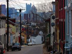 a city street with cars parked on both sides and buildings in the background, as well as power lines