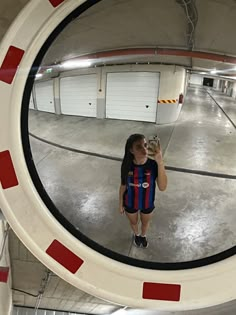 a woman is taking a selfie in the reflection of a mirror that has red and white stripes on it