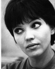 a black and white photo of a woman with short hair wearing a sweater looking at the camera