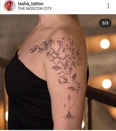 a woman's shoulder with flowers and leaves on her left arm, the tattoo is done in black ink