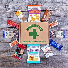 an emergency snack box filled with snacks on top of a wooden table next to other food items