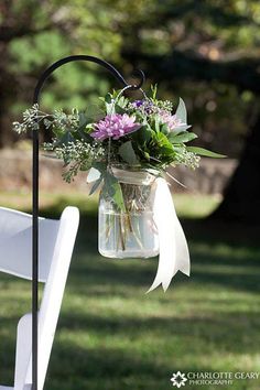 a vase filled with purple flowers sitting on top of a white chair next to a tree