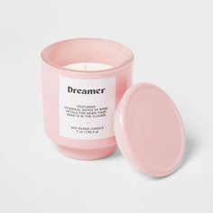 a pink candle sitting on top of a table next to a white container with the lid open