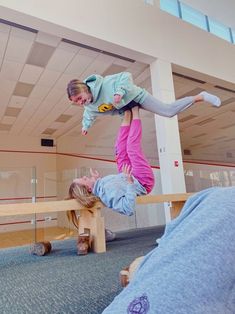 two girls are doing tricks on a bench