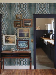 an entry way with blue wallpaper and pictures on the wall next to a wooden table