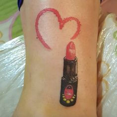 a woman's leg with a heart shaped lipstick tattoo on her left arm and the word love written in red ink