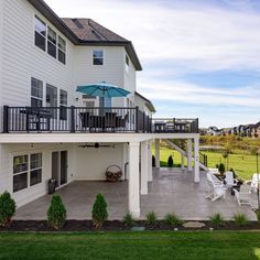 a large white house with an umbrella on the balcony and lawn in front of it