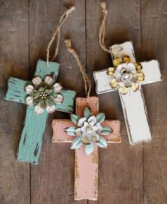 three wooden crosses with flowers on them hanging from twine strings against a wood background