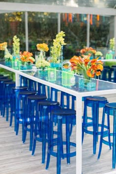 a long table with blue chairs and vases filled with flowers on top of it