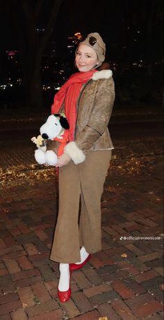 a woman is holding a stuffed animal in her hands while standing on a brick walkway