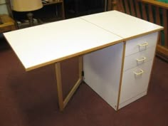 a white desk with two drawers and a lamp next to it in a room filled with furniture