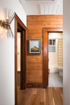 an open door leading to a bathroom with wood paneling on the walls and floor