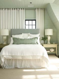 a white bed sitting in a bedroom next to a window with curtains on top of it