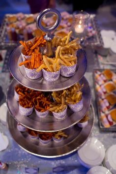 a three tiered tray filled with cupcakes and snacks