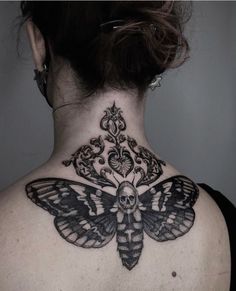 the back of a woman's neck with a moth tattoo on it