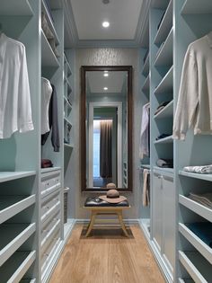 an empty walk in closet with lots of shelves and clothes hanging on the walls, along with a bench