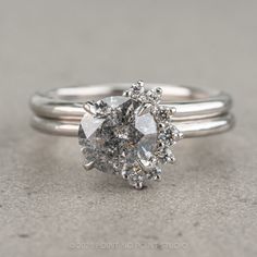 a white gold ring with an oval cut diamond surrounded by smaller round diamonds on the band