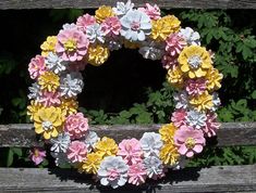 a wreath made out of paper flowers sitting on top of a wooden bench