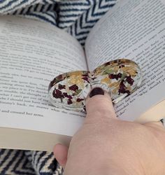 a person is reading a book and holding an object in their hand that looks like a butterfly