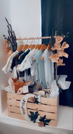 a wooden crate filled with lots of baby clothes and stuffed animals on top of it