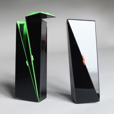 two black vases sitting side by side on a gray surface, one with green accents