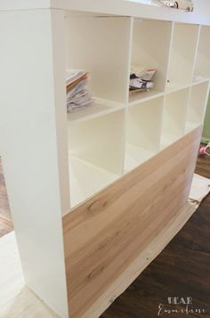 a white bookcase with wooden shelves on the top and bottom shelf is being built