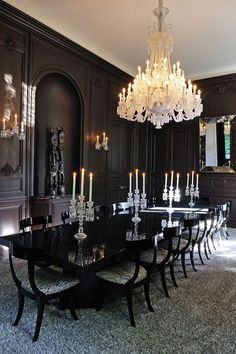 an elegant dining room with chandelier and black table surrounded by chairs in the middle